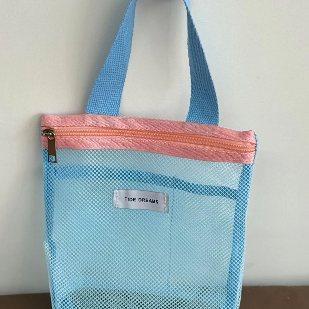 Blue mesh bag with pink zipper on a white background
