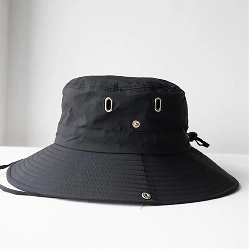 Black bucket hat with chin strap on a light gray background