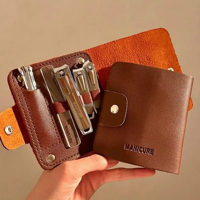 Brown manicure kit with nail clippers and tools in a leather case, held by a hand against a beige background.