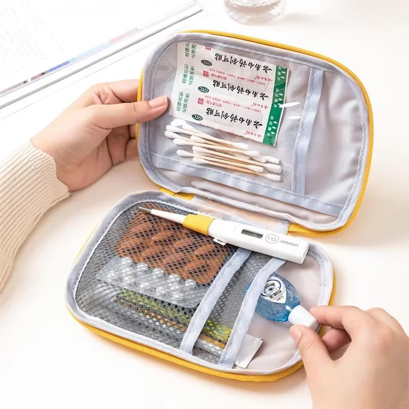 First aid kit with various supplies including bandages and a thermometer, held by a person.