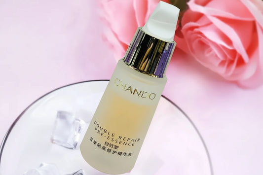 CHANDO Double Repair Pre-Essence skincare serum bottle with a white pump and metallic collar, shown on a pink background with rose petals and Chinese text overlay.