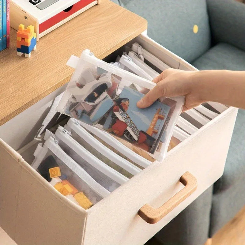 Person organizing photo albums in  mesh zipper pouches with a wooden handle.