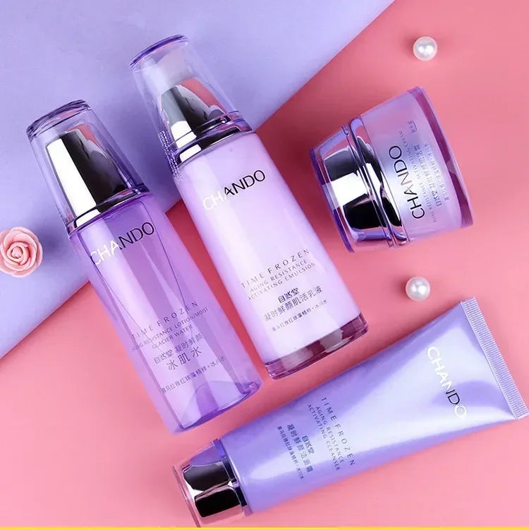 Four Chiando skincare products in purple packaging arranged on a pink and lavender background: two tall bottles, one jar, and one tube, with pearl-like decorative beads and a small rose.