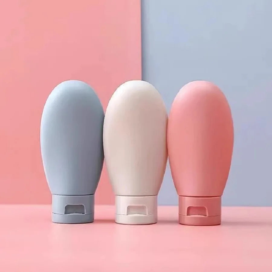 Three cylindrical containers in gray, beige, and pink on a pink and blue background
