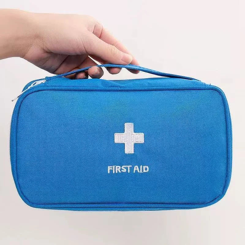 Blue first aid kit with a white cross and 'FIRST AID' text, held by a hand on a light gray background.