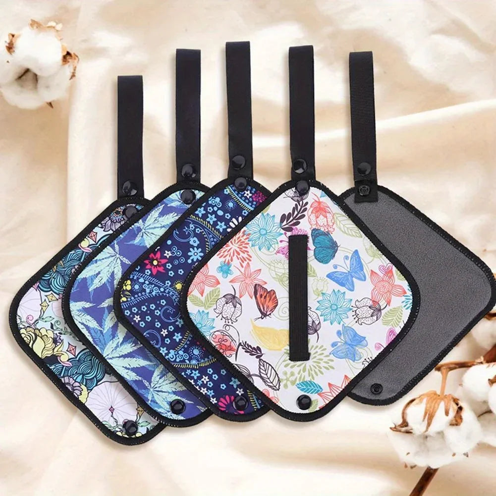 Set of five floral and butterfly patterned luggage tags on a soft beige background.