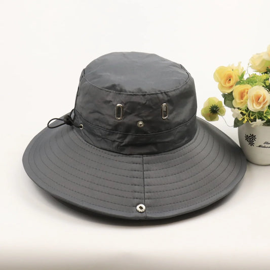 Gray wide-brimmed hat on a white surface with a small potted plant in the background