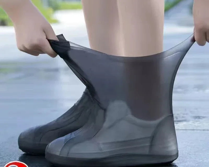 Person putting on a black rain boot with a transparent cover over it.