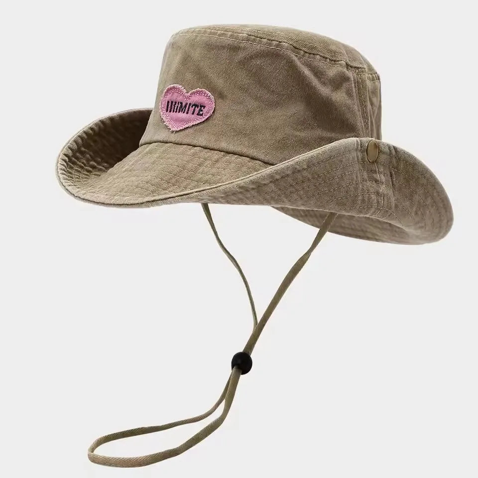 Beige bucket hat with a pink heart patch on a light gray background