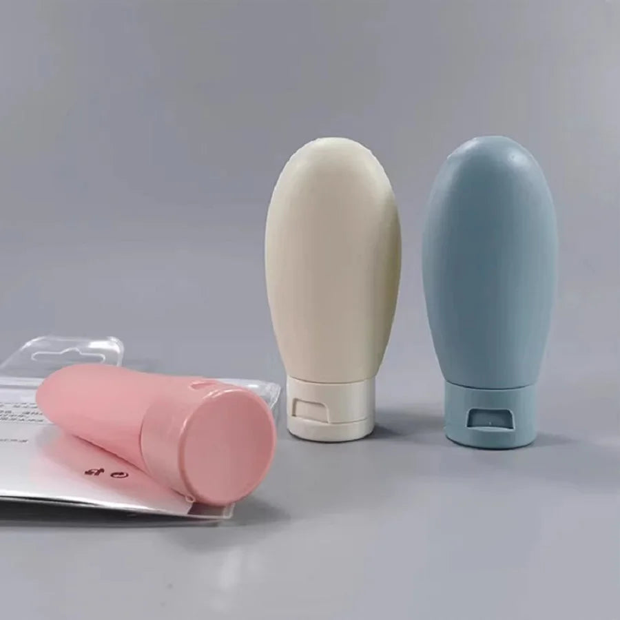Three cosmetic bottles in pink, beige, and blue on a gray background