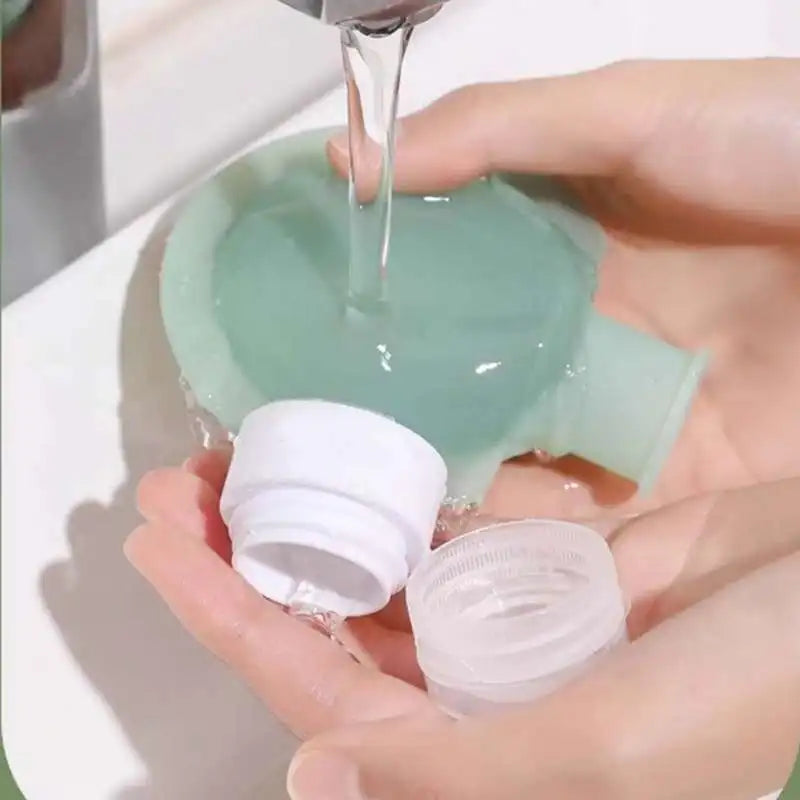 A close-up of hands holding a translucent mint-green bottle under running water, with two white screw caps in front.