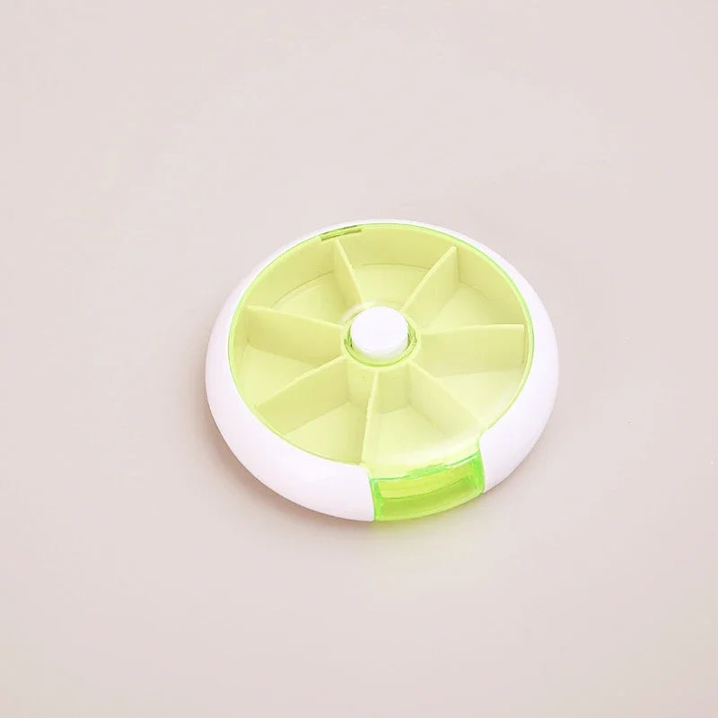 A round plastic organizer tray with multiple compartments, featuring a white outer rim, a pale yellow-green interior, and a translucent green latch, shown on a plain light beige background.