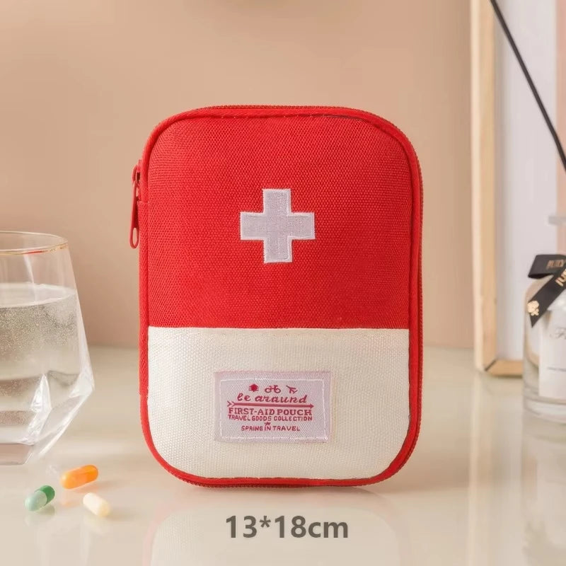 Red and white first aid kit with a cross symbol on a beige surface.