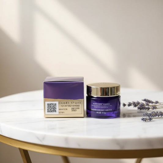 A cosmetic cream jar with a gold lid and a purple box placed on a laptop keyboard. The jar has Chinese text on the label, and the box has a barcode label with a QR code.