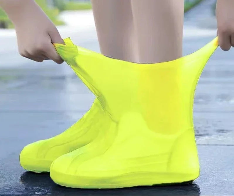 Person wearing bright yellow rain boot covers on a wet pavement.