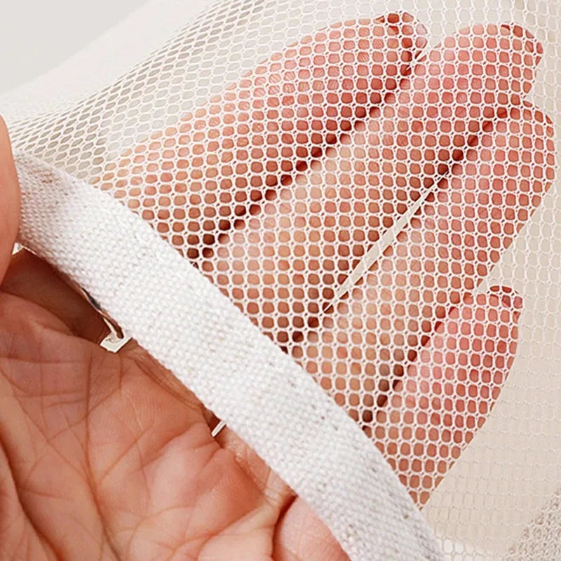 Close-up of a white mesh fabric with a matching white elastic trim, held by a hand to show texture and flexibility.