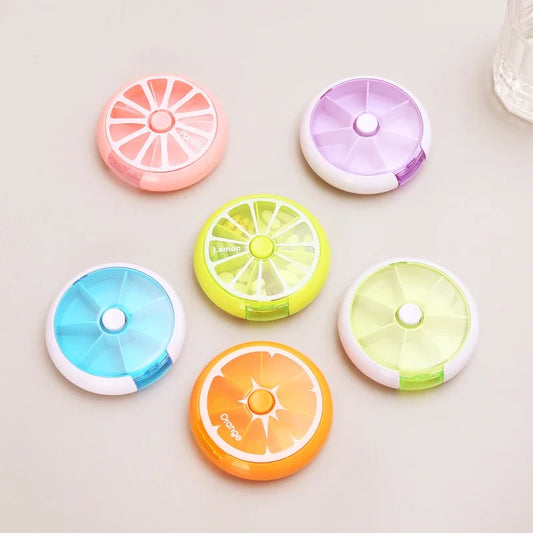 Six small round citrus-themed organizer cases in pink, purple, blue, green, yellow, and orange, arranged on a light beige surface.