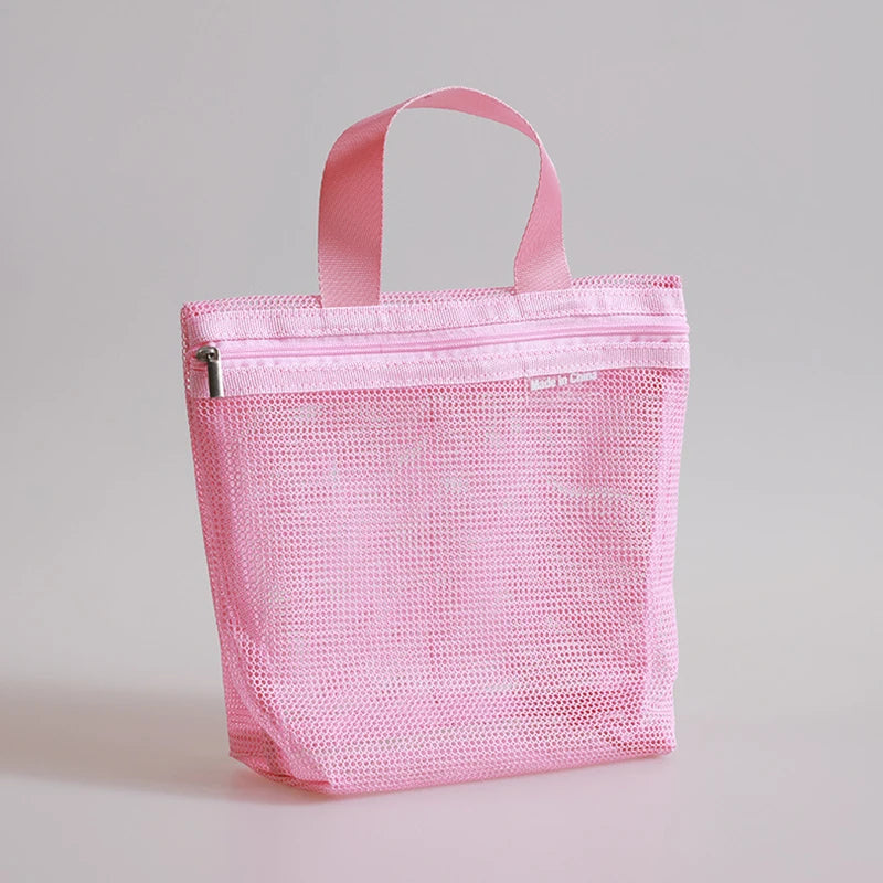 A pink mesh zippered pouch with two top handles, photographed on a clean light gray studio background.