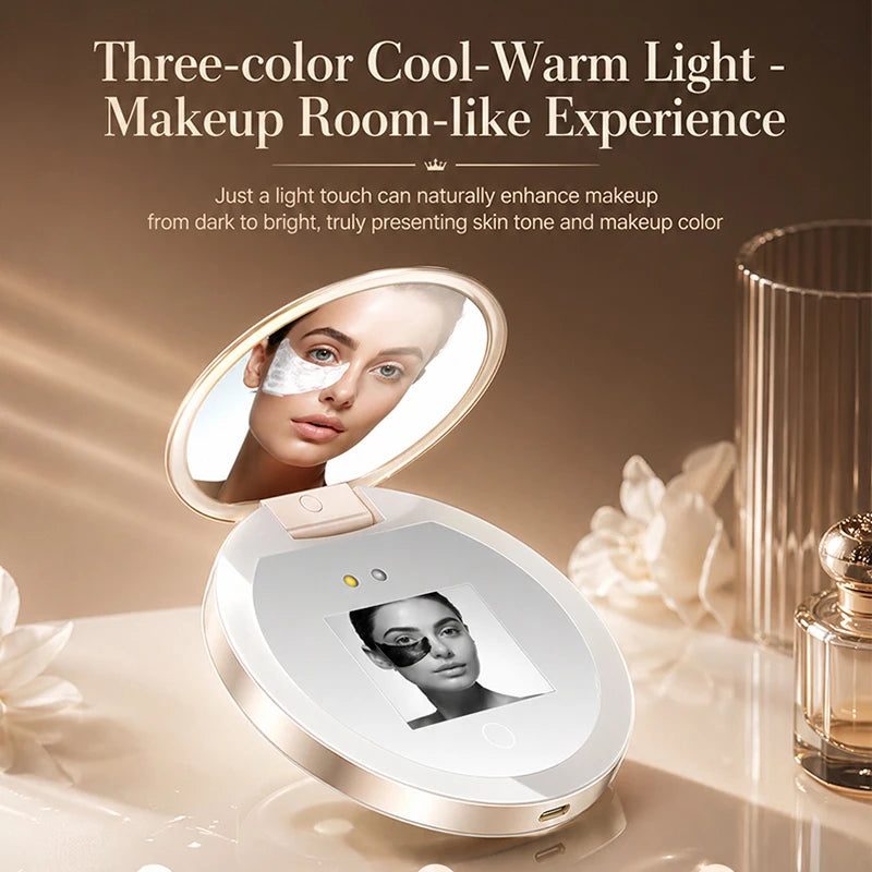 A compact makeup mirror device with an open oval mirror and a built-in display screen, shown on a beige tabletop with decorative flowers and a perfume bottle. Text at the top reads 'Three-color Cool-Warm Light - Makeup Room-like Experience' with descriptive copy below.