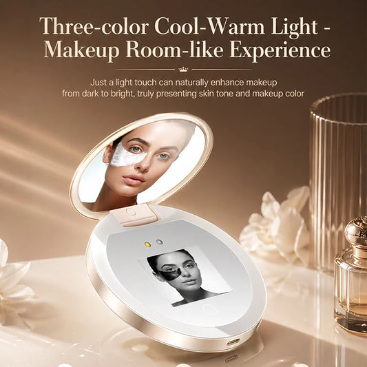 A compact makeup mirror device with an open oval mirror and a built-in display screen, shown on a beige tabletop with decorative flowers and a perfume bottle. Text at the top reads 'Three-color Cool-Warm Light - Makeup Room-like Experience' with descriptive copy below.