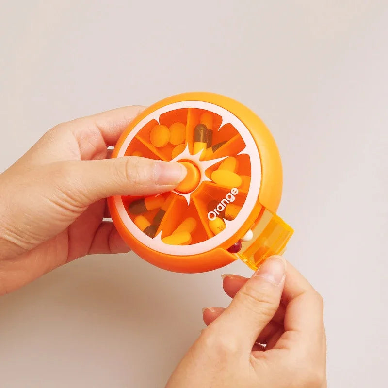 Orange pill organizer held by a hand against a plain background