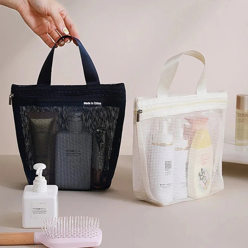 Two mesh travel toiletry bags with handles are shown on a tabletop. A hand is holding the black bag on the left, and a white bag on the right contains shampoo and lotion bottles.