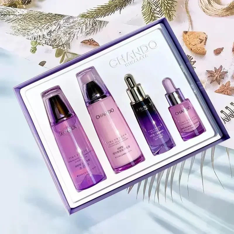A boxed skincare set from CHANDO NINJAJA with four purple-toned bottles and dropper bottles arranged in a white tray inside a lavender gift box, styled with dried botanicals on a pale blue surface.
