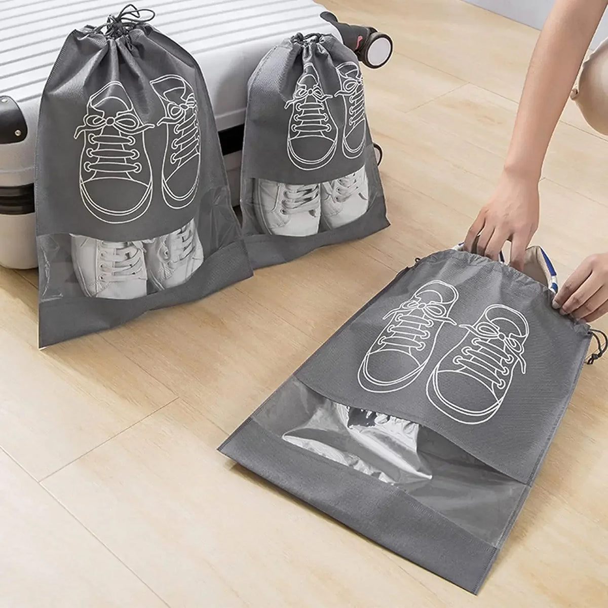 Gray shoe bags with white shoe illustrations being used to pack shoes into a suitcase.