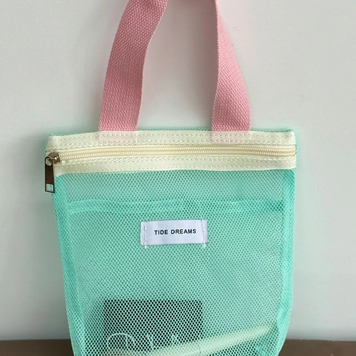 Green mesh bag with pink handles on a white background