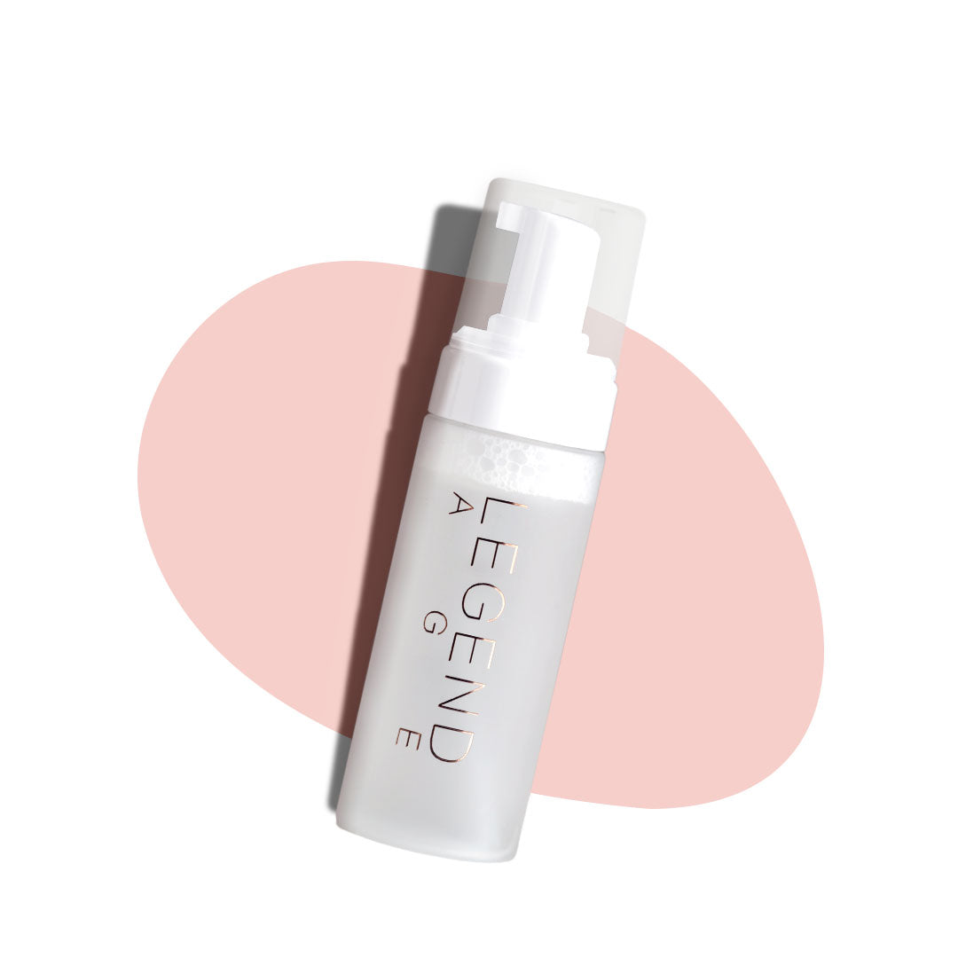 Skincare bottle labeled 'Legend' on a white background with a pink circular object.